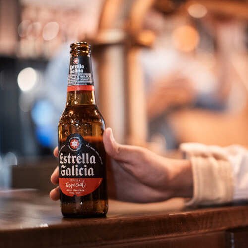 Botella de cerveza artesanal servida en barra con fondo desenfocado.